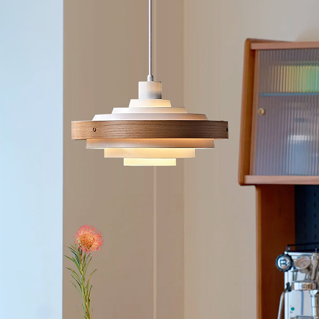 A Clérachic white and walnut ring pendant lit warm, with a glass-fronted cabinet and a pink flower in a vase beside it.