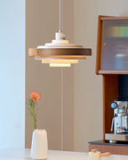 A Clérachic white and walnut pendant hangs by a window nook with a white vase, a pink flower and a coffee machine.