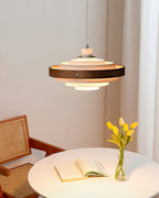 A Clérachic white and walnut pendant hangs above a round white table with an open book and a vase of yellow tulips.
