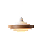 White and oak stacked ring pendant from Clérachic, a pale wood band around white tiers, on a plain white backdrop.