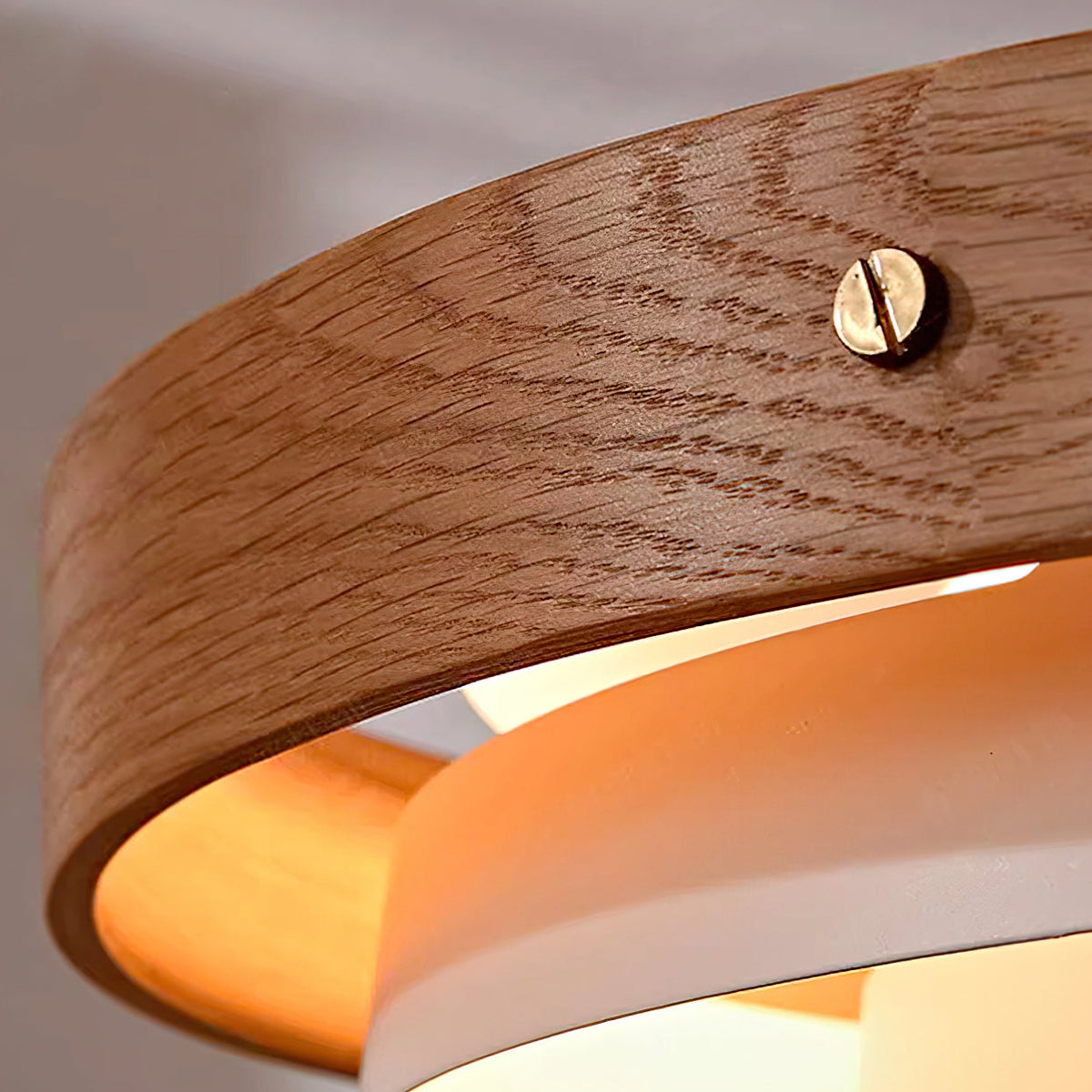 Close view of the oak band on this Clérachic pendant, showing its grain and a small brass screw, with the warm white tier inside.