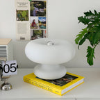 Clérachic donut lamp on a yellow gardening book on a white shelf, beside a large green leaf and a flip clock.
