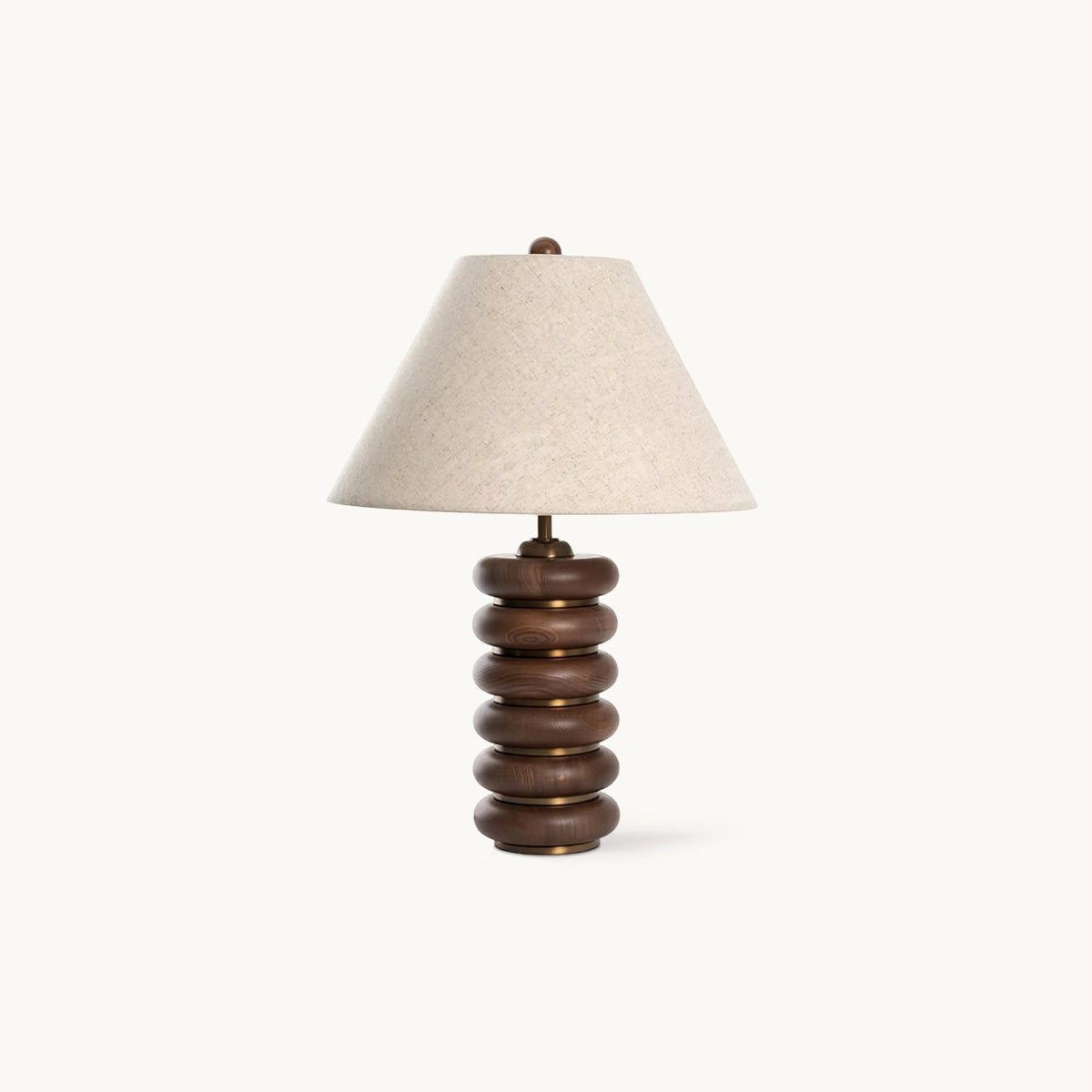 This Clérachic table lamp on a plain white backdrop, with a stacked walnut wood base, gold bands and a white linen shade.