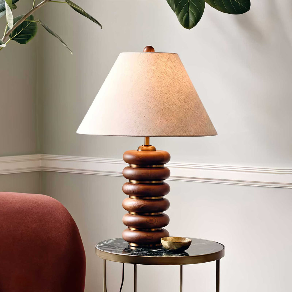 Close, straight-on view of this Clérachic table lamp on a round black-topped side table, with a small brass dish beside it.