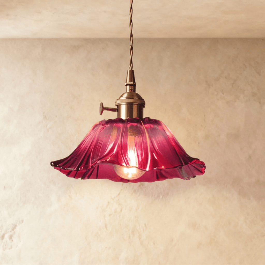 Clérachic flared magenta glass pendant on a twisted cord with a brass switch holder, lit by a warm bulb against a limewashed wall.
