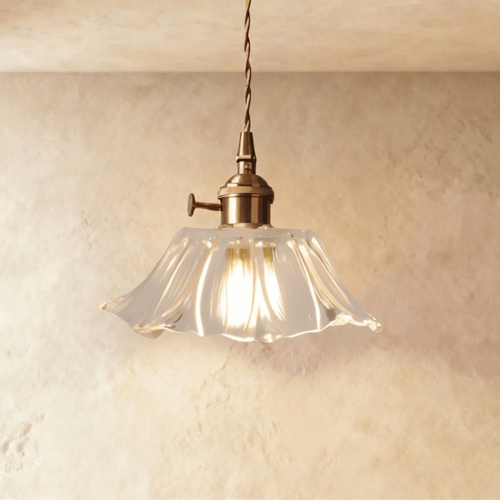 Clérachic clear ribbed glass pendant with a flared hem, brass switch holder and twisted cord, glowing warmly against a limewashed wall.
