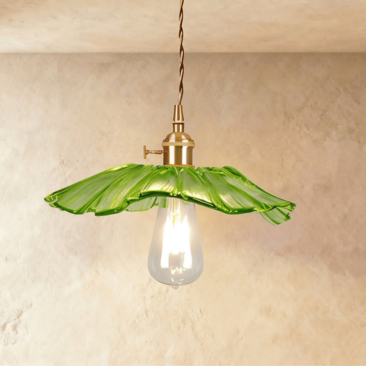 Clérachic shallow green glass pendant with a frilled rim on a brass holder, a long clear teardrop bulb glowing beneath it.