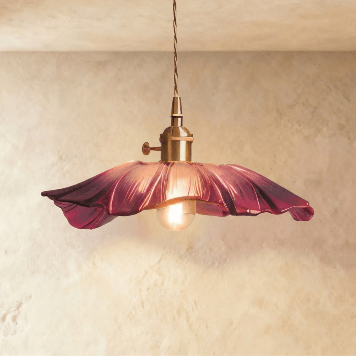 Clérachic wide magenta-purple glass pendant with a rippled edge on a brass holder, bulb softly lit, hung against limewash.