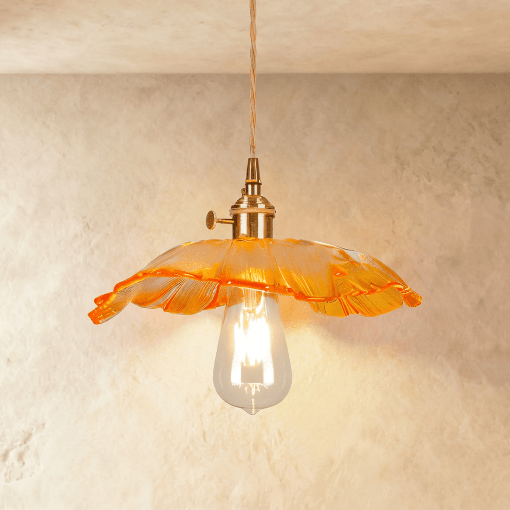 Clérachic shallow orange glass pendant with a bright frilled edge, gold-toned holder and a lit teardrop bulb on twisted cord.