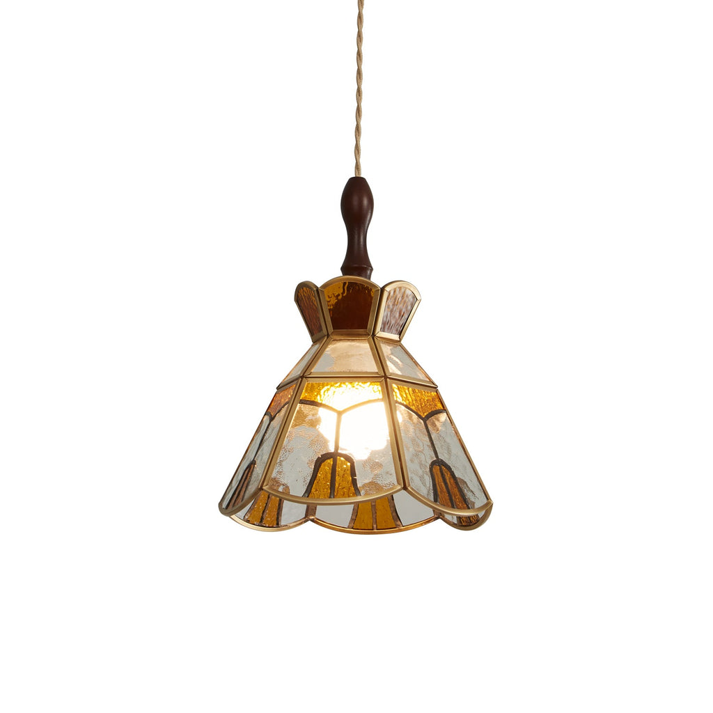Clérachic stained glass pendant with a stepped amber crown and clear and amber panels in brass came, lit on a white backdrop.