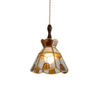 Clérachic stained glass pendant with a stepped amber crown and clear and amber panels in brass came, lit on a white backdrop.