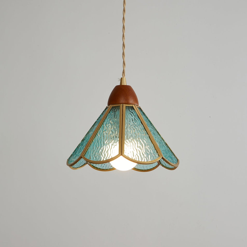 Teal Clérachic pendant lit on a mid-grey backdrop, its rippled glass petals lit from within and its wooden cap above.