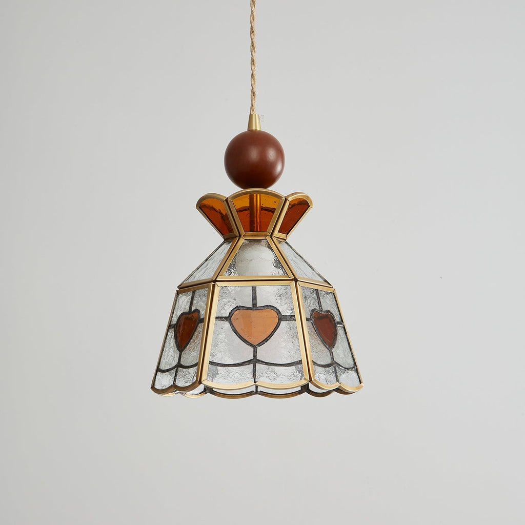 Unlit Clérachic heart-panel pendant on grey, with a wooden ball finial, an amber crown and clear textured glass in brass.