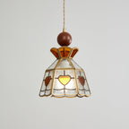 Lit Clérachic heart-panel pendant on grey, the amber hearts glowing at the front of its clear glass shade.