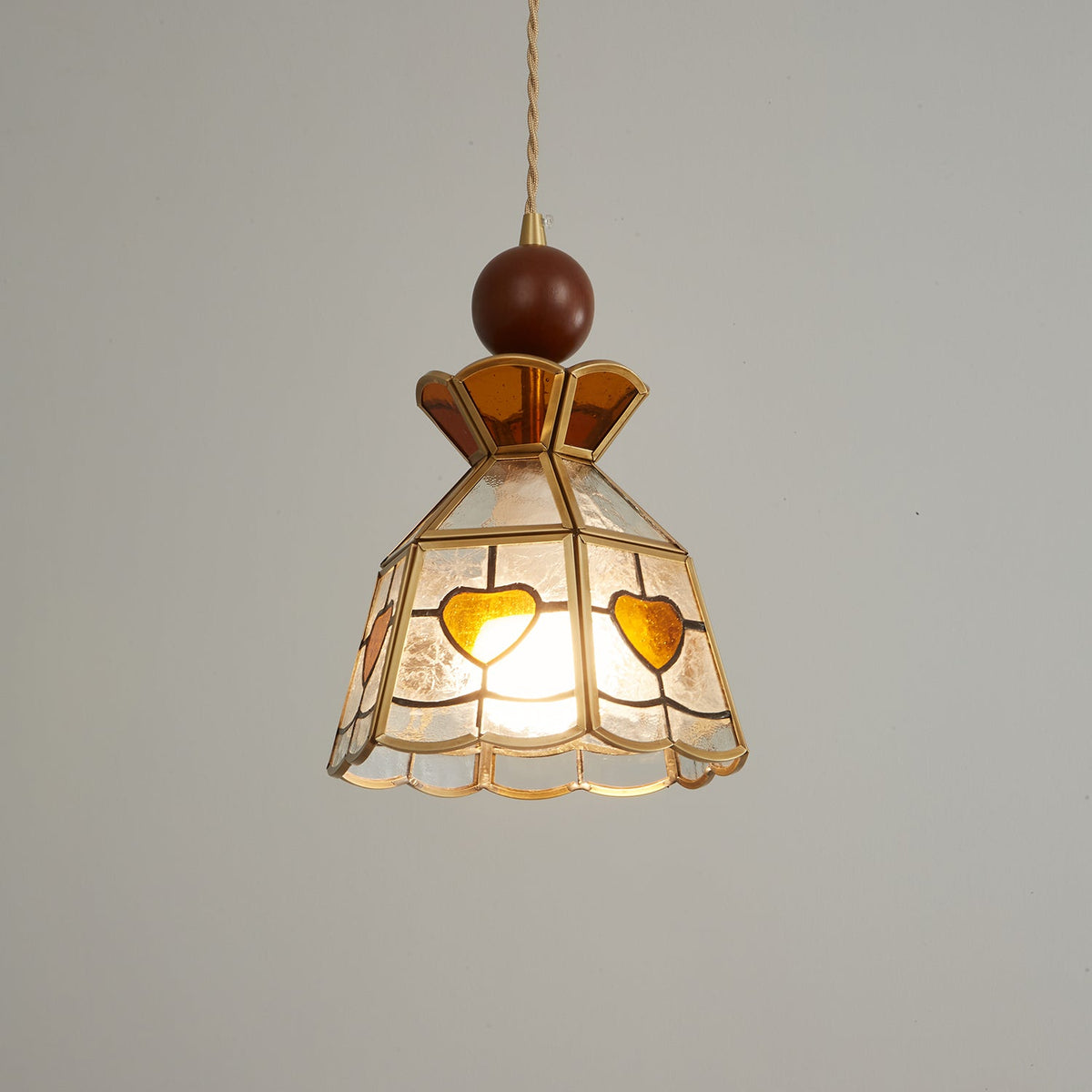 Brightly lit Clérachic heart-panel pendant with an amber crown, the light spilling warm through its textured glass.