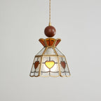 Clérachic heart-panel pendant switched off, showing its pale textured glass, amber hearts and brass frame on grey.
