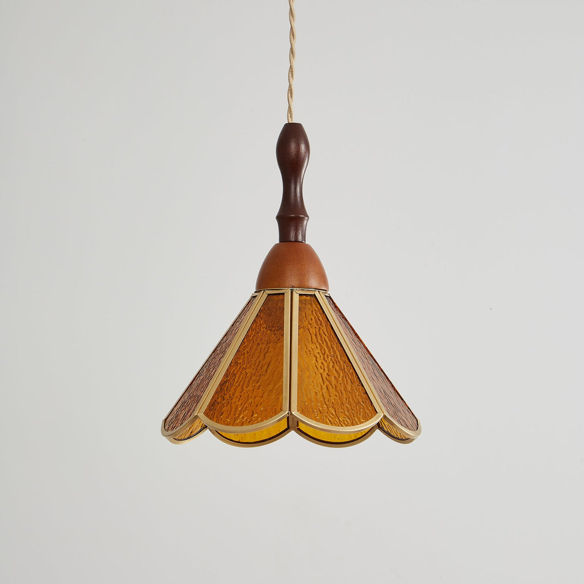 Unlit amber Clérachic pendant with a flared scalloped shade of textured glass and a turned wooden finial, on pale grey.