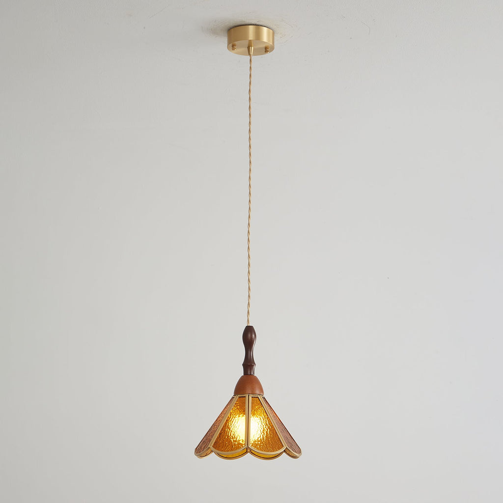 Amber Clérachic pendant on a long cord from a brass canopy, small against a pale grey wall.