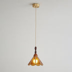 Amber Clérachic pendant on a long cord from a brass canopy, small against a pale grey wall.