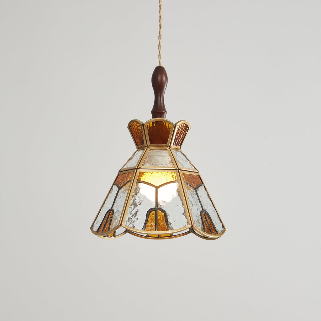 Lit Clérachic stained glass pendant with a stepped amber crown, a warm bulb glowing through its clear and amber panels.