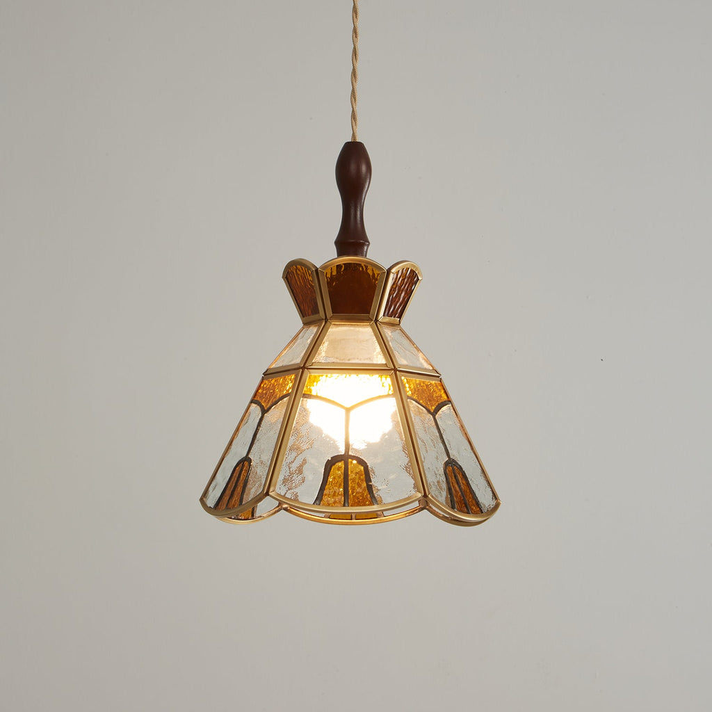 Clérachic stained glass pendant with a stepped crown, glowing warm on a darker grey backdrop, with a wooden finial above.