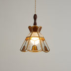 Clérachic stained glass pendant with a stepped crown, glowing warm on a darker grey backdrop, with a wooden finial above.