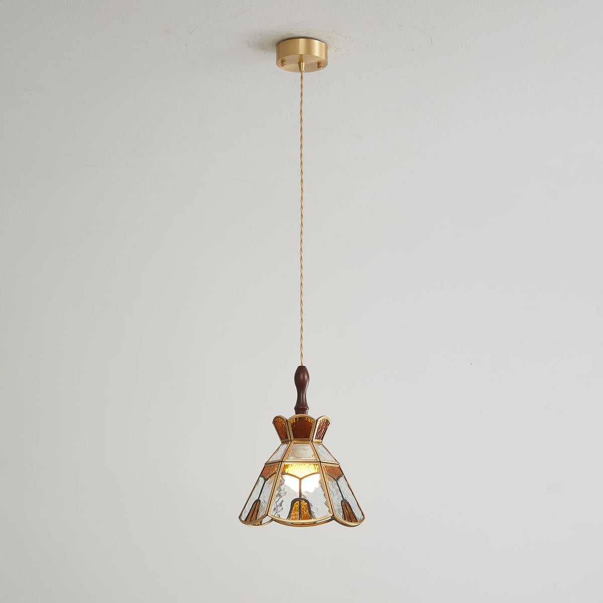 Small Clérachic stepped-crown pendant on a long cord from a brass ceiling canopy, shown against a pale wall.