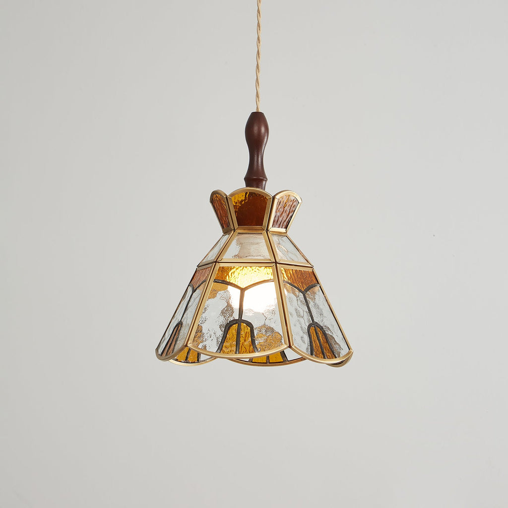 Clérachic pendant with clear and amber glass panels and a stepped crown, its bulb glowing behind rippled glass.