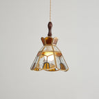 Clérachic pendant with clear and amber glass panels and a stepped crown, its bulb glowing behind rippled glass.