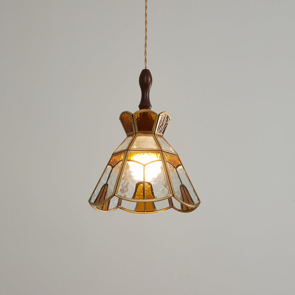 Lit Clérachic pendant with a stepped crown and amber teardrop panels, a soft glow showing through the glass.