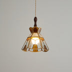 Lit Clérachic pendant with a stepped crown and amber teardrop panels, a soft glow showing through the glass.