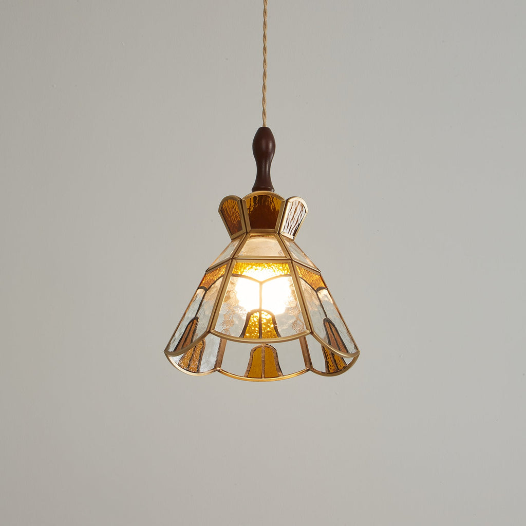 Clérachic stepped-crown pendant with a warm amber glow inside, its scalloped hem and brass trim lit from within.