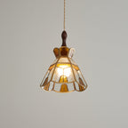 Clérachic stepped-crown pendant with a warm amber glow inside, its scalloped hem and brass trim lit from within.