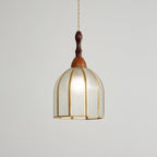 Faintly lit Clérachic domed pendant with textured clear glass between brass ribs, on a pale grey backdrop.