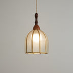 Lit Clérachic domed pendant glowing a soft gold, its brass ribs and textured glass clear against a grey wall.