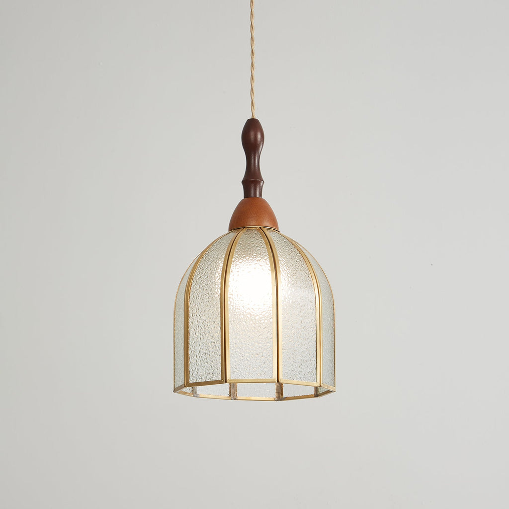 Clérachic domed pendant, lit, the bulb glowing through textured glass in an eight-rib brass frame.