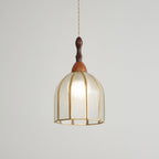 Clérachic domed pendant, lit, the bulb glowing through textured glass in an eight-rib brass frame.