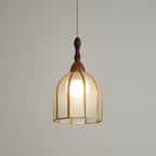 Clérachic domed pendant with brass ribs and rippled glass, the bulb glowing against a mid-grey backdrop.