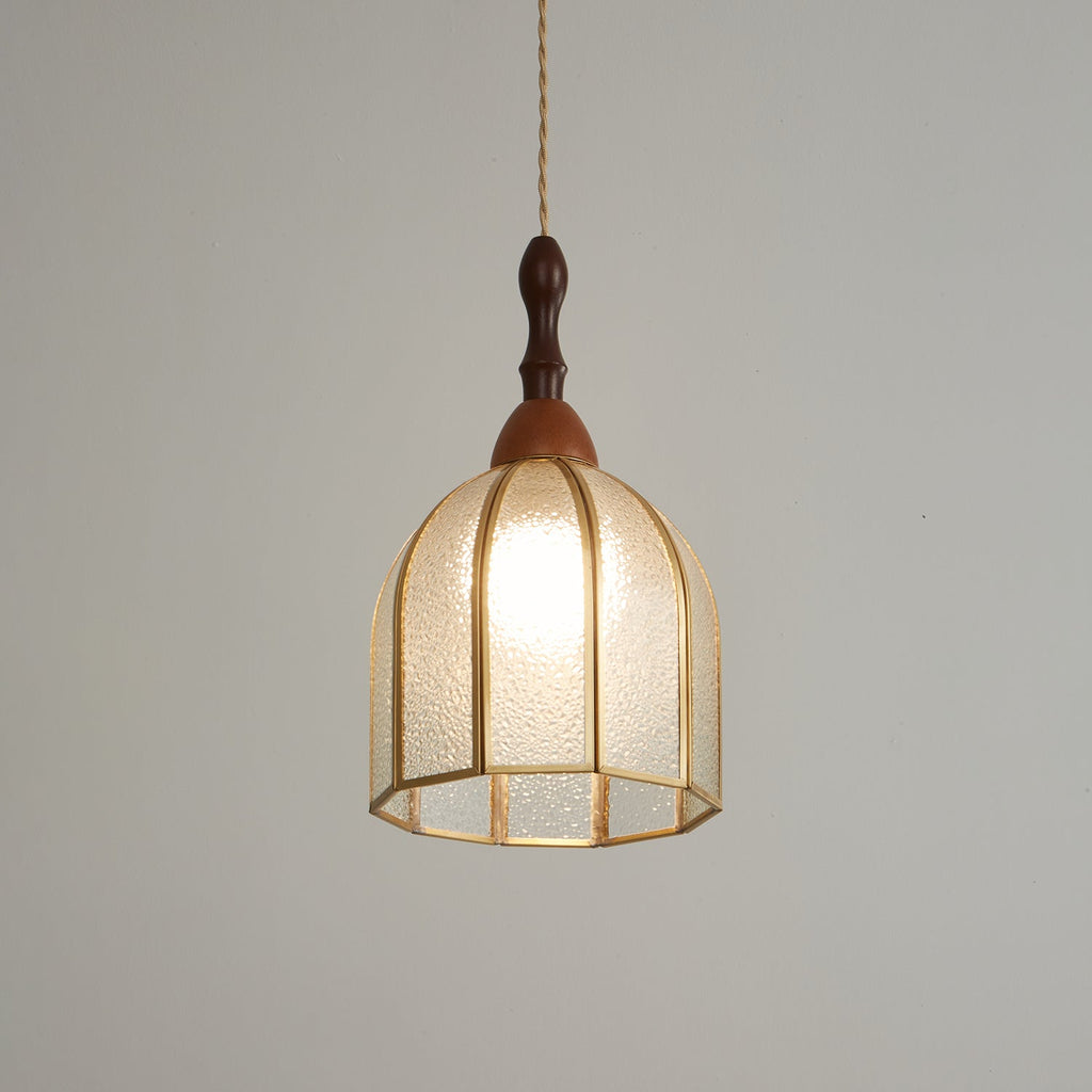 Warm-lit Clérachic domed pendant with brass ribs, photographed on a grey backdrop with its wooden cap above.