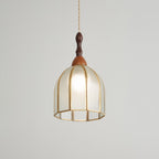 Clérachic domed pendant lit, its textured glass and open brass base catching the light on a pale backdrop.