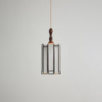 Unlit Clérachic pendant with a frosted glass shade in a slim dark frame, a wooden cap and a turned finial.