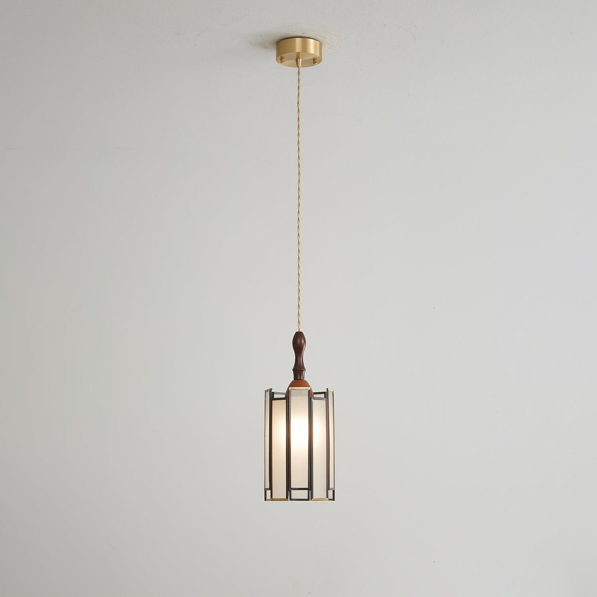 Small Clérachic frosted-panel pendant on a long twisted cord from a brass ceiling canopy, against a pale grey wall.