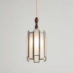 Clérachic frosted-panel pendant on a pale backdrop, its wooden cap and glowing panels in a dark frame with brass edges.