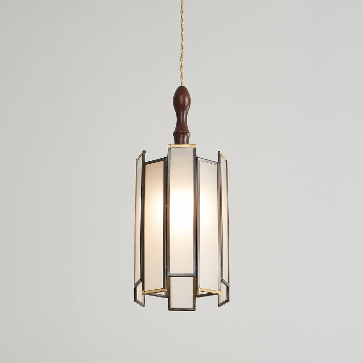 Clérachic frosted-panel pendant on a pale backdrop, its wooden cap and glowing panels in a dark frame with brass edges.