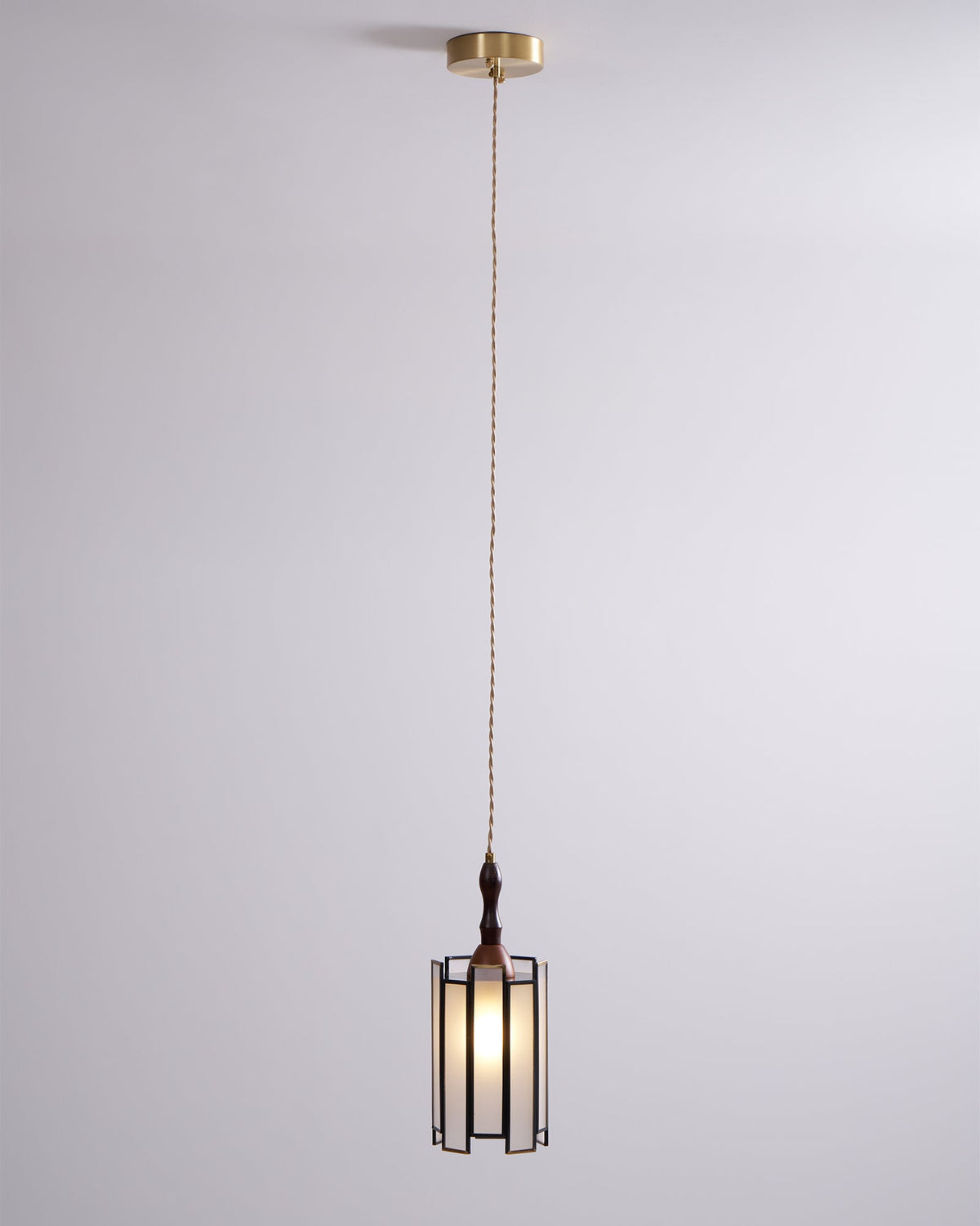 Lit Clérachic frosted-panel pendant on a long cord from a brass canopy, glowing against a soft lilac-grey wall.