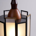 Close view of the wooden cap and dark metal top of this Clérachic pendant, with its brass-edged frosted panels glowing below.