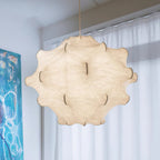 A glowing white Clérachic pendant fills the frame beside sheer curtains and a turquoise painting.