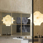 A lit white Clérachic pendant is reflected in a gold-framed mirrored panel, next to a second one at the right edge.