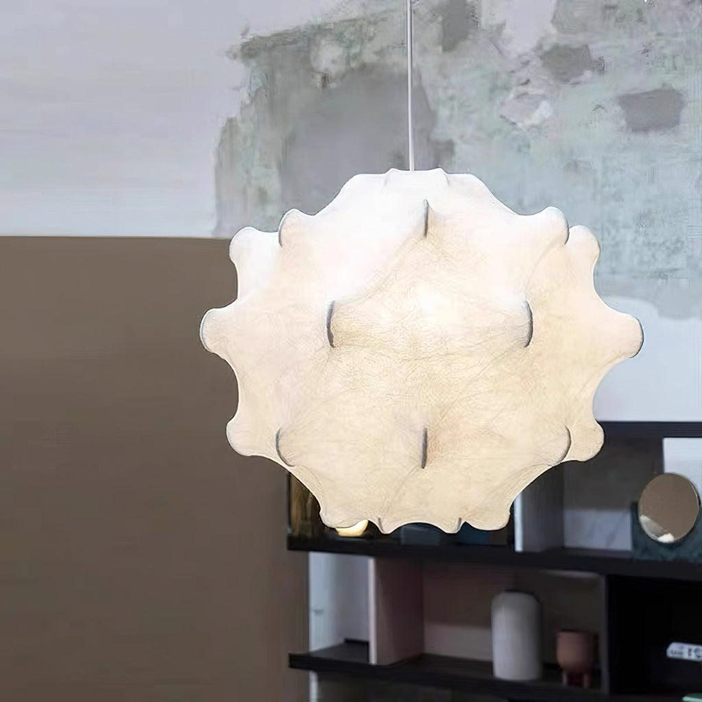 Close view of a white Clérachic pendant with its soft, dimpled shade, hung above a dark shelf with vases.