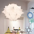 A large white Clérachic pendant hangs in a bright showroom, beside round patterned mirrors and coloured shades.